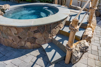 Benham S - Cape May Courthouse, NJ - A hot tub surrounded by a stone wall with a rope railing and steps leading up to it