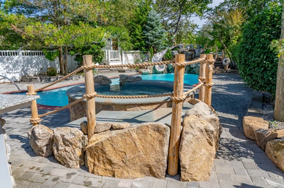 Benham T - Cape May Courthouse, NJ - A backyard with a swimming pool surrounded by rocks and a rope fence