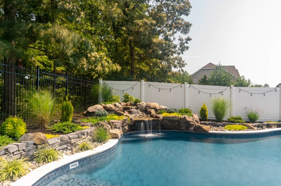 Benton C - Egg Harbor, NJ - A backyard with a pool and a waterfall surrounded by lush greenery