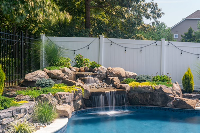 Benton D - Egg Harbor, NJ - A backyard with a pool and waterfall surrounded by lush greenery