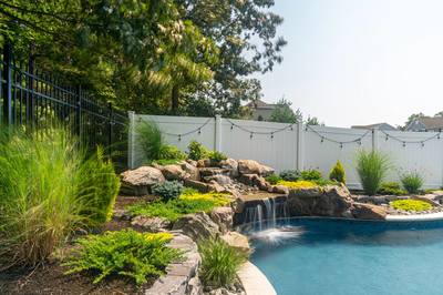 Benton E - Egg Harbor, NJ - A backyard with a pool and a waterfall surrounded by plants and rocks