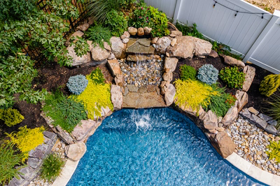 Benton J - Egg Harbor, NJ - A small backyard with a waterfall surrounded by plants and rocks