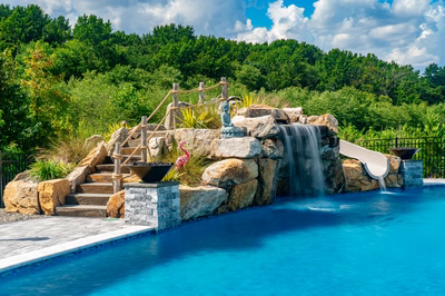 Berlin C - Robbinsville, NJ - A swimming pool with a waterfall and a play area surrounded by lush greenery