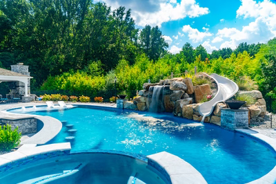 Berlin I - Robbinsville, NJ - A swimming pool with a waterfall and a water slide surrounded by lush greenery