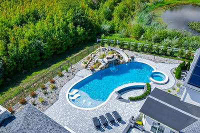 Berlin O - Robbinsville, NJ - A bird's eye view of a backyard with a swimming pool surrounded by lush greenery and a pond