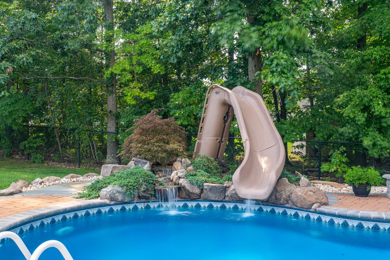 Natural stone boulder waterfall cascading into a blue pool surrounded by lush greenery