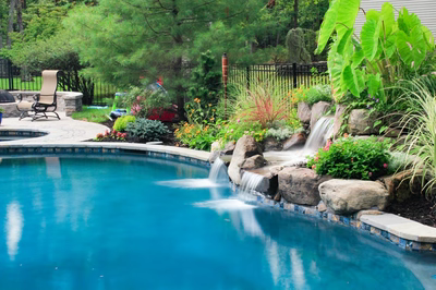 Bowman F - Medford, NJ - A swimming pool with a waterfall surrounded by lush greenery and colorful flowers