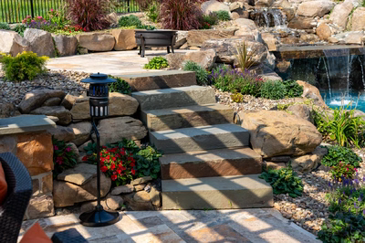 Bridge G - Lewisburg, PA - A stone patio with steps leading to a waterfall surrounded by flowers and plants
