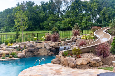 Bridge I - Lewisburg, PA - A backyard with a water feature and a slide, surrounded by lush greenery