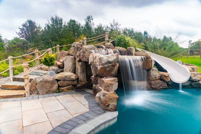 Bruar C - Millstone, NJ - A large rock waterfall with a white water slide in a backyard setting