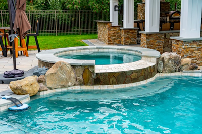 Bruar I - Millstone, NJ - A swimming pool with a waterfall and a stone patio area.