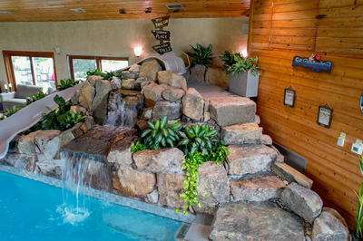 Bumpass D - Monroeville, NJ - A large indoor swimming pool with a waterfall feature and a water slide