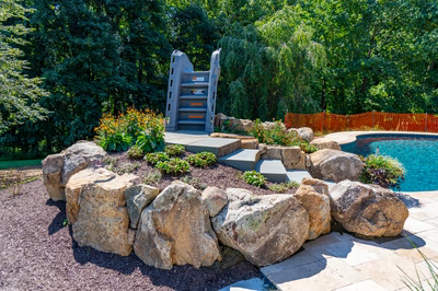 Burney - Matawan, NJ - A rock garden next to a swimming pool with a play structure in the background