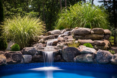 Carson B - Tabernacle, NJ - A swimming pool with a waterfall in the middle surrounded by rocks and plants