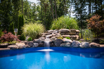 Carson C - Tabernacle, NJ - A swimming pool with a waterfall in the middle surrounded by lush greenery