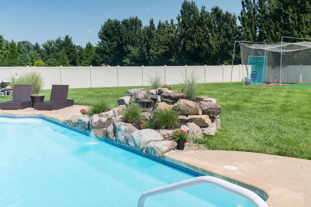 Beach D - Lumberton, NJ - A backyard with a swimming pool and a rock waterfall feature