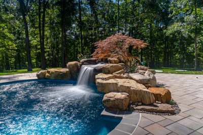 Castor D - Fallston, MD - A swimming pool surrounded by lush green trees and a waterfall.