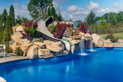 Chania D - Hamilton, NJ - A swimming pool with a water feature and a slide surrounded by flowers
