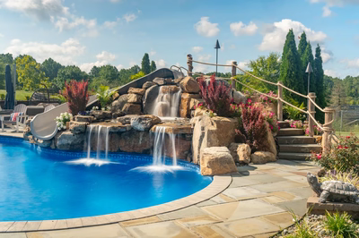 Chania F - Hamilton, NJ - A swimming pool with a waterfall and a water feature surrounded by lush greenery