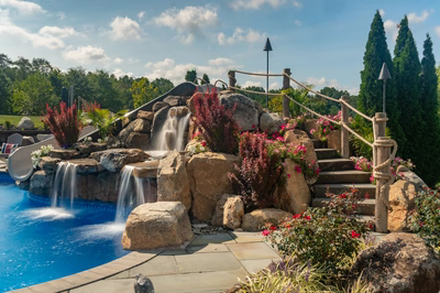 Chania G - Hamilton, NJ - A scenic outdoor swimming pool with a waterfall and a rope bridge