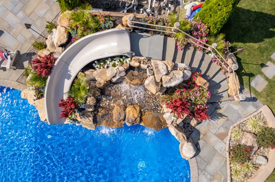 Chania I - Hamilton, NJ - A swimming pool with a water feature surrounded by flowers and greenery