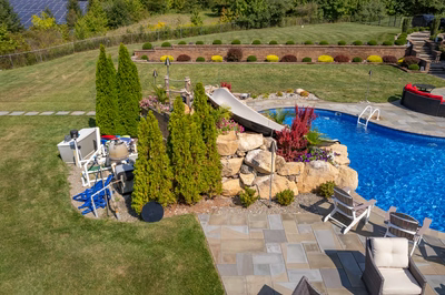 Chania N - Hamilton, NJ - A backyard with a swimming pool surrounded by lush greenery and landscaping
