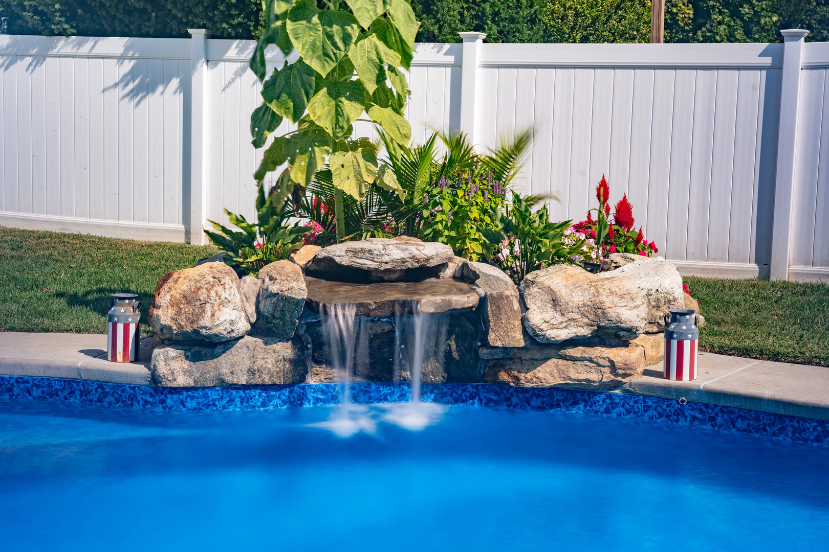 Two-tiered natural stone boulder waterfall cascading into a pool surrounded by lush tropical plants