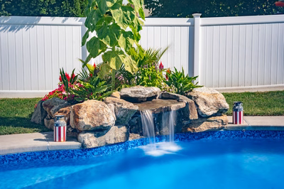 Chapel B - West Long Branch - A pool with a waterfall in the middle surrounded by flowers and greenery