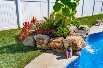 Chapel C - West Long Branch - A flower bed next to a swimming pool with a flag-themed water feature