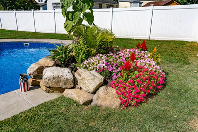 Chapel G - West Long Branch - A flower bed next to a swimming pool with rocks and plants around it