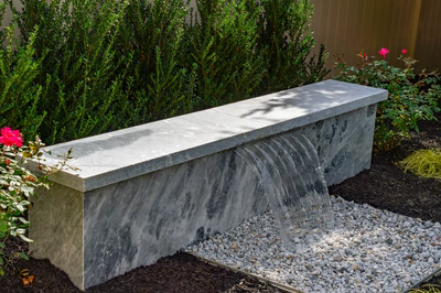 Formal G -  - A concrete bench with a small waterfall in a garden setting