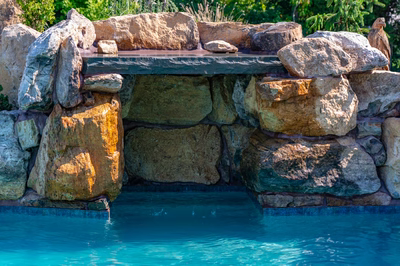 Cispus E - Mantua, NJ - A stone structure over a swimming pool with clear blue water.
