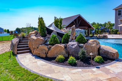 Cispus H - Mantua, NJ - A backyard with a large rock garden and a pool area.