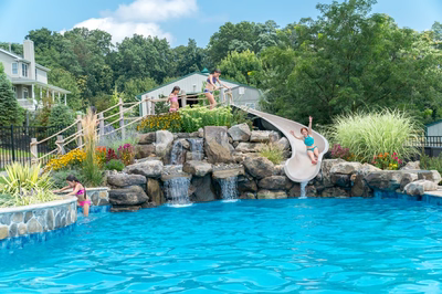 Clarendon B - Cream Ridge, NJ - A children's play area with a water feature and a slide in a backyard setting
