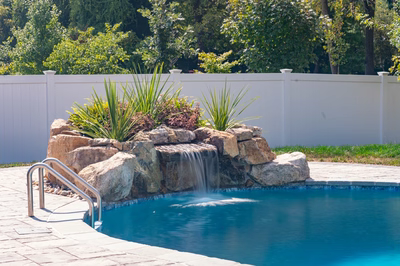 Cliff B - Bel Aire, MD - A swimming pool with a waterfall in the middle of it surrounded by greenery and a white fence
