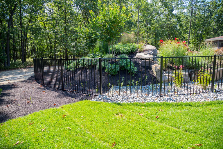 Cascading natural stone boulder waterfall emptying into a pool framed by lush garden plants