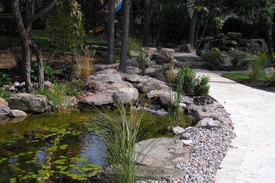 Coeur A - Voorhees, NJ - A stone path leading to a small pond surrounded by greenery and rocks