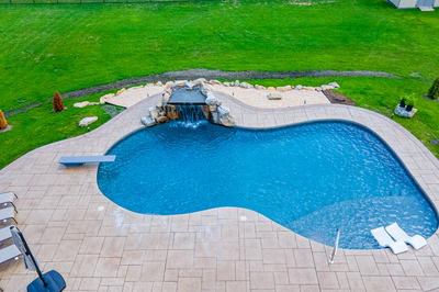 Comet J - Medford, NJ - A swimming pool with a waterfall in the middle of a lush green yard