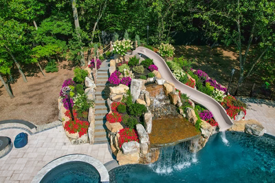 Copper I - Cream Ridge, NJ - A beautiful backyard with a waterfall and a water slide surrounded by lush greenery