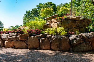 Copper K - Cream Ridge, NJ - A stone retaining wall with flowers in the foreground and trees in the background