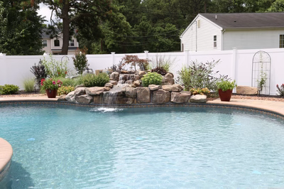 Crabtree A - Bayville, NJ - A swimming pool with a waterfall in the middle surrounded by plants and flowers