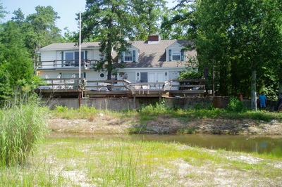Dagg A - New Jersey - A large white house with a deck next to a body of water.