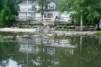 Dagg C - New Jersey - A large white house sitting next to a body of water surrounded by trees and rocks