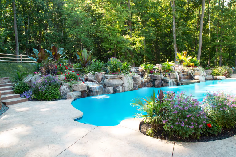 Natural stone boulder waterfalls cascading into a freeform pool with lush tropical landscaping