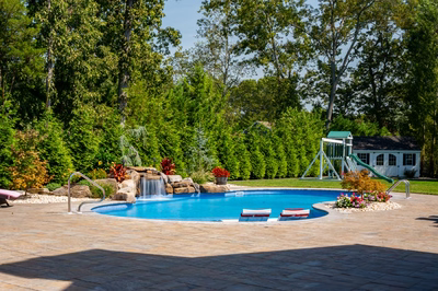 Datanla E - Brick, NJ - A backyard with a swimming pool surrounded by lush greenery and trees