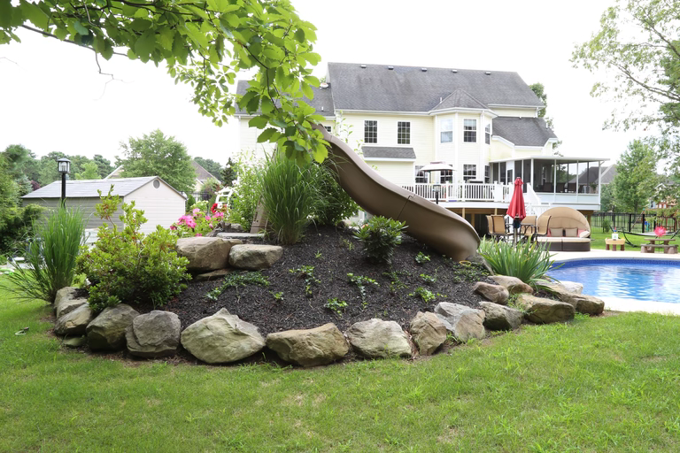 ading boulder waterfall flowing into a pool amidst lush green garden landscaping." 1. Cascading 2. boulder 4. waterfall