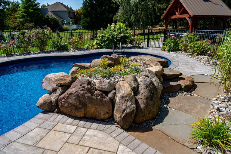 Natural stone boulder waterfall cascading into a blue pool surrounded by lush greenery