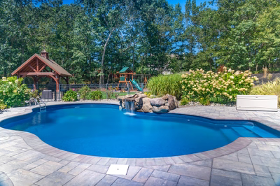 Decorah H - Wall, NJ - A backyard with a swimming pool and a gazebo surrounded by lush greenery