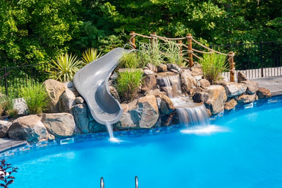 Desoto D - Perryville, MD - A swimming pool with a water feature and a water slide surrounded by lush greenery