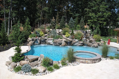 Flume A - Franklinville, NJ - A backyard with a swimming pool surrounded by lush greenery and rocks